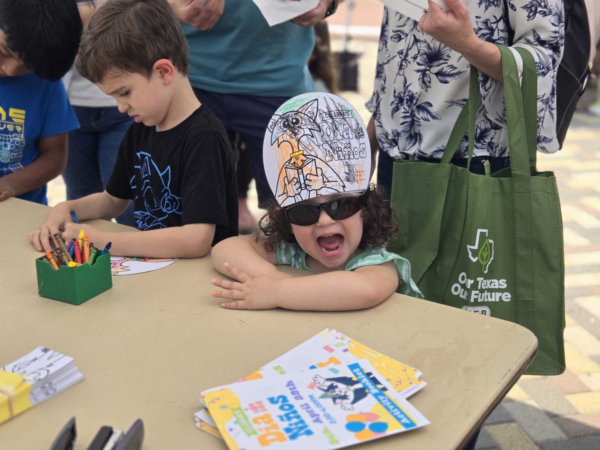 Children color Día de los Niños activity pages during a family celebration at Main Library.